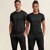 A man and a woman modeling matching black athletic short-sleeve crewneck shirts and black pants against a light beige studio background.